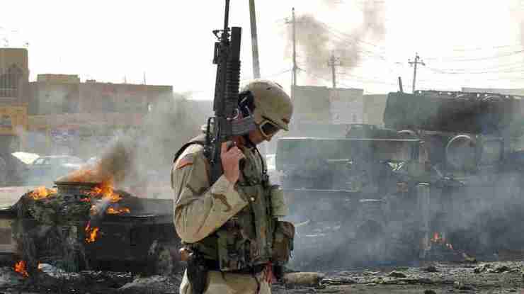 A U.S. Army soldier guards the remains of a burned-out military ammunition truck after it was attacked in Fallujah, Iraq, on Oct. 19, 2003. Fallujah and its surrounds were the site of some of the bloodiest fighting for U.S. troops during the Iraq war. Khalid Mohammed/AP