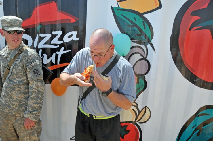 Sgt. William Paulk of the 900th Maintenance Company, Alabama National Guard, eats his first slice of Pizza Hut pepperoni pizza at the grand opening of the facility at Forward Operating Base Deh Dadi II. The Pizza Hut completes the food court on the FOB, as the 530th Combat Sustainment Support Battalion continues to expand construction projects there.